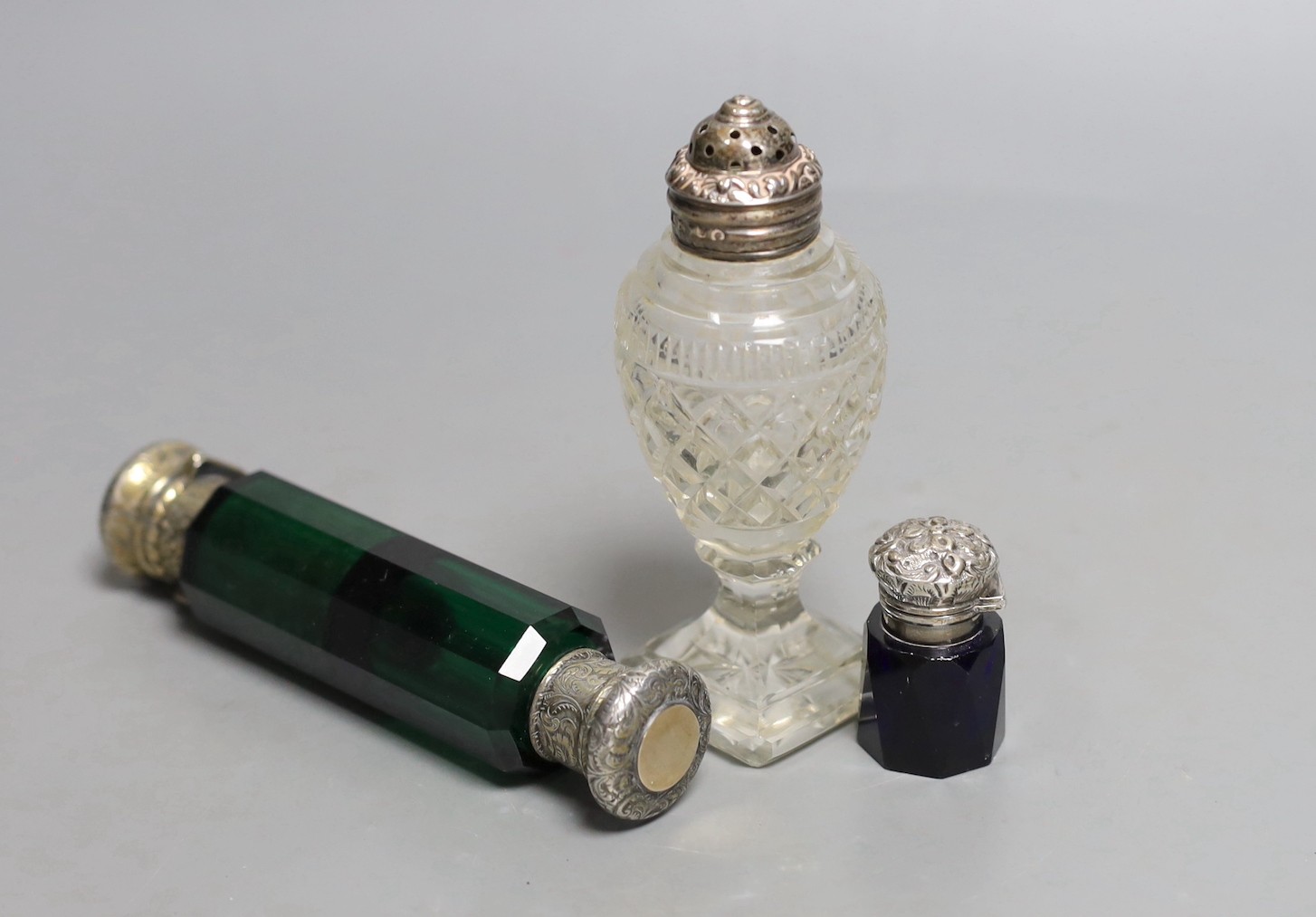 A Victorian silver mounted double ended green glass scent bottle, 13.8cm, a Georgian silver topped cut glass salt and a silver topped blue glass scent bottle (lacking stopper).